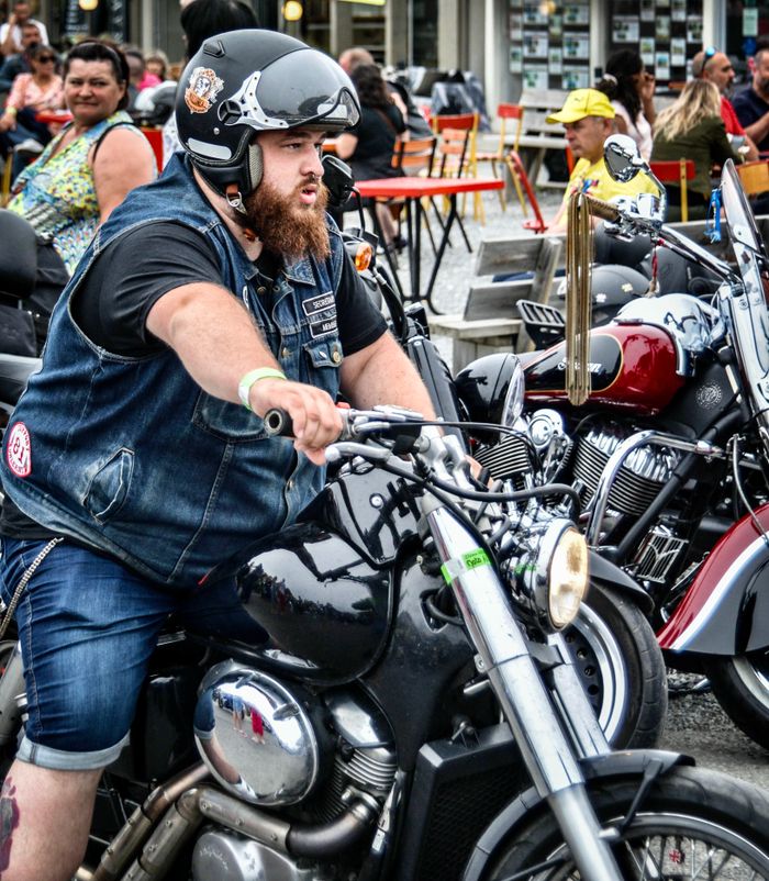 hero-about Bearded rider on a motorcycle at a vibrant motorcycle event in Soulac-sur-Mer, France.