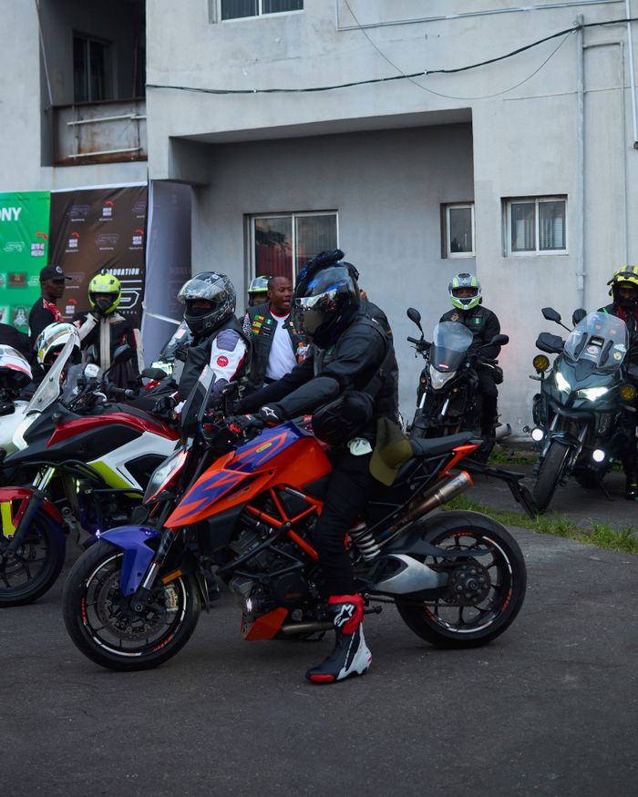 about-02 Motorcyclists in gear gather with their sports bikes in an urban setting, ready to ride.