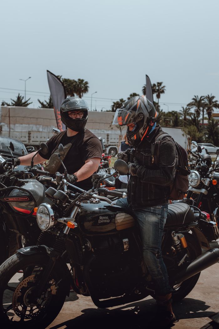 services-04 Two bikers in helmets and jackets prepare for a ride on vintage motorcycles.