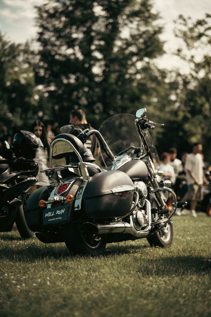 A classic motorcycle displayed at an outdoor motorcycle event with a crowd in the background.