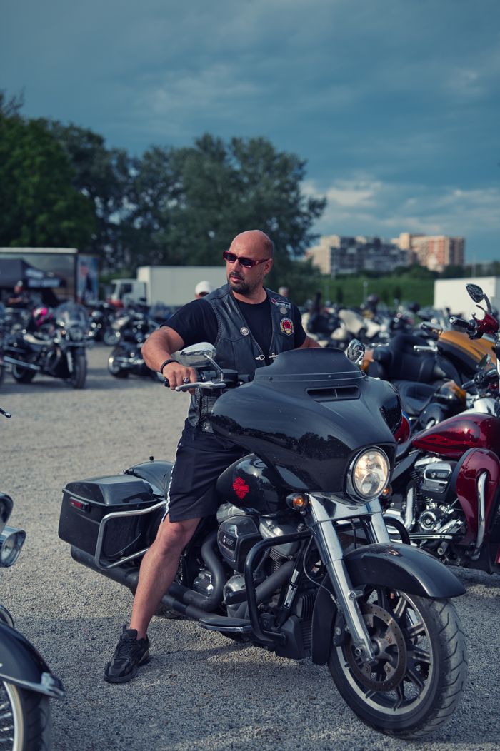 approach-img Biker on a motorcycle at a massive outdoor rally with multiple bikes.