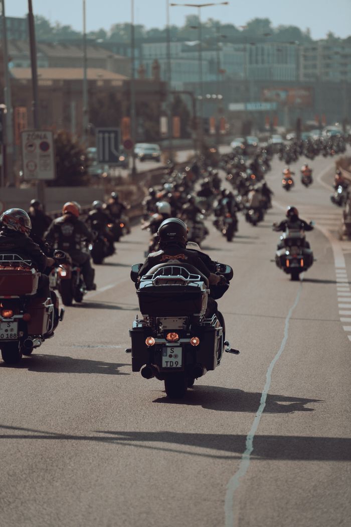 services-02 A large group of bikers on a sunny day riding through an urban highway environment.